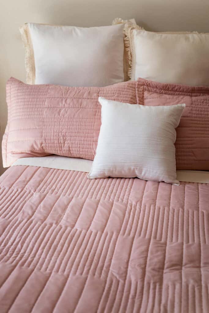cozy made bed with pink sheets 